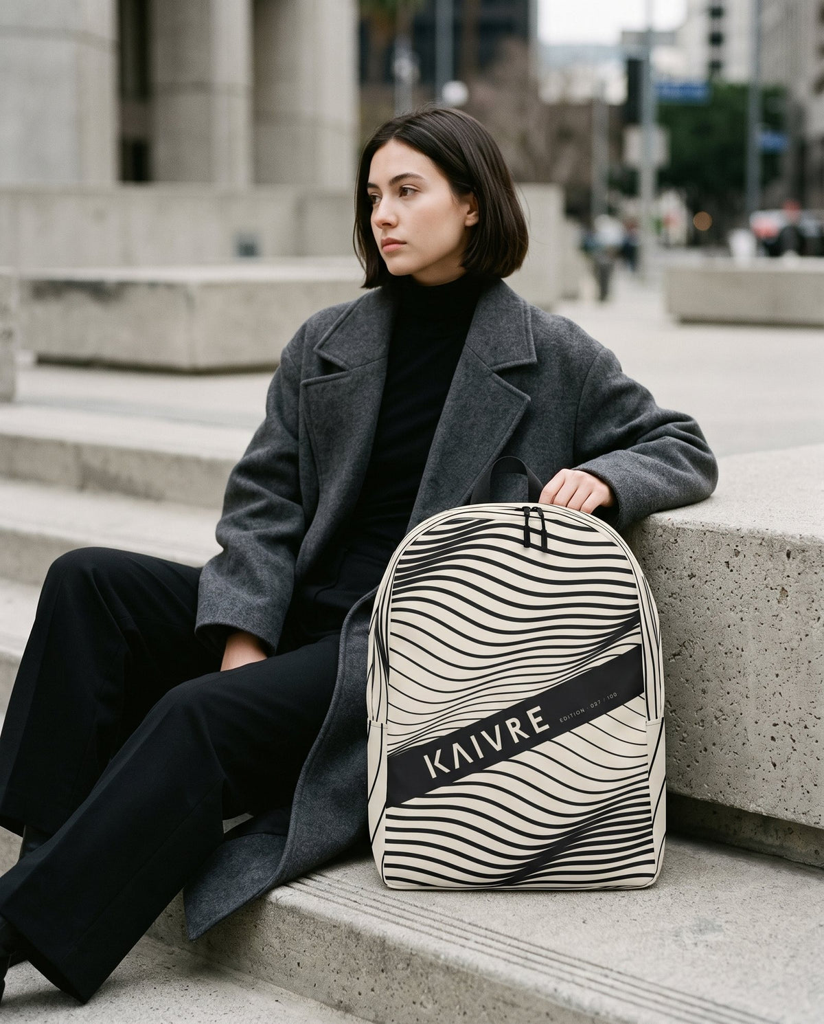 A woman in a charcoal wool coat holding the Swell Keeper Pack on city steps